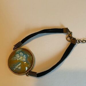 Hand painted acrylic design on glass bracelet.  Attached to metal.  Adjustable